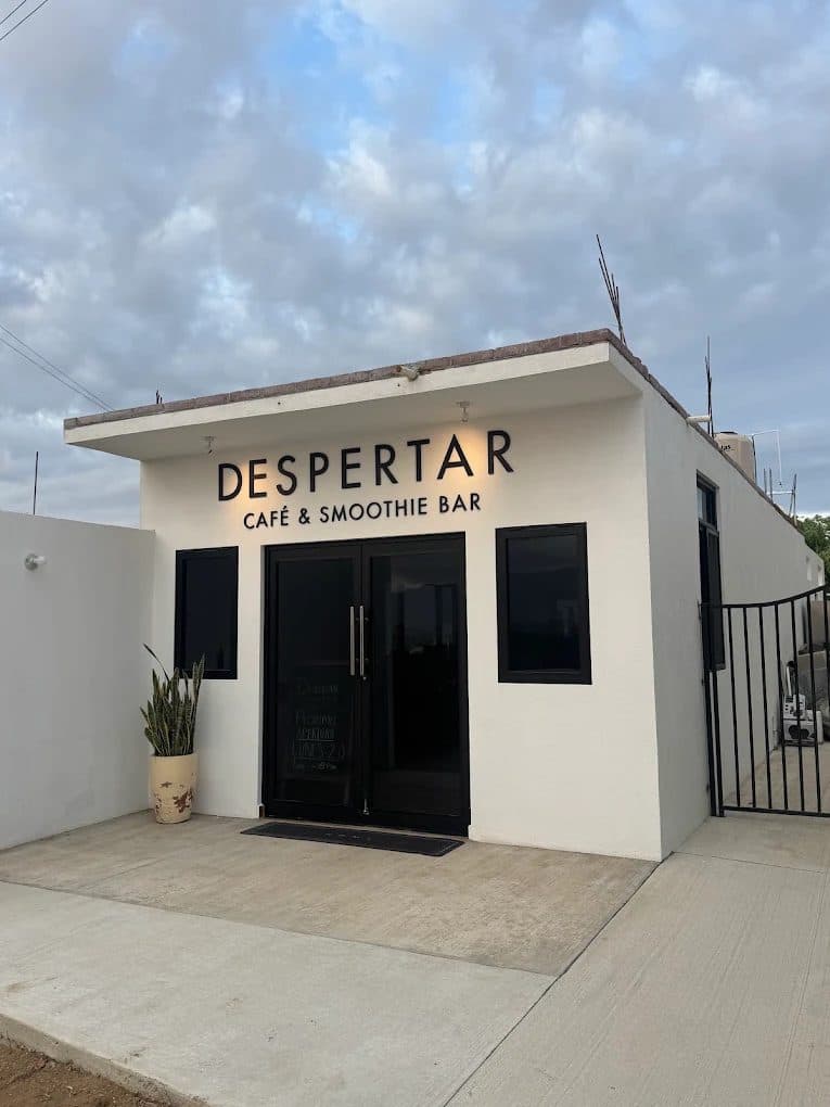 The Despertar café — a white building with black window frames and a potted plant by the door.